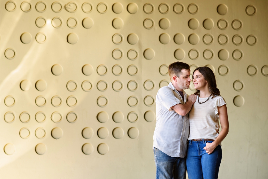 A cute couple stand in front of a cool wall in fishtown.